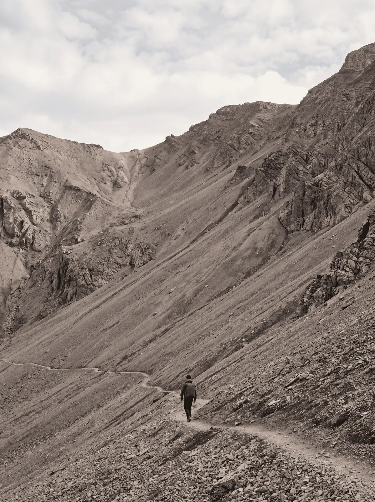 A walker small against a vast scree mountain slope, ProPack on their back
